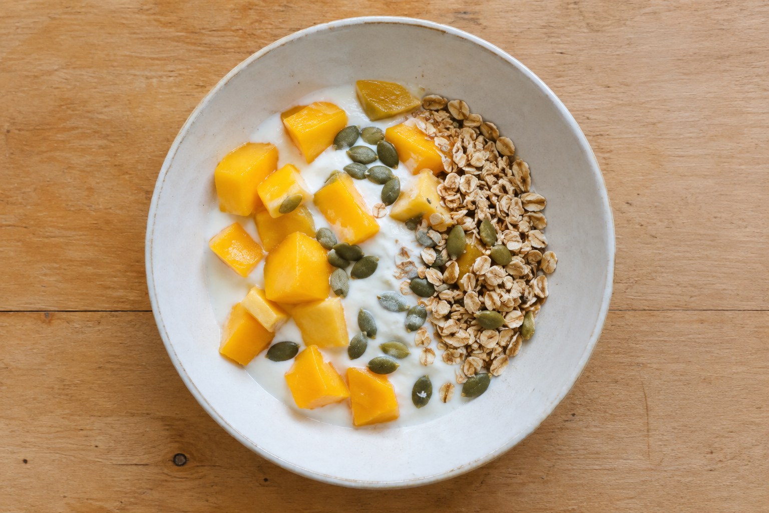 Bowl de yogur con mango, avena y pepitas